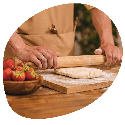 Person Using a Wooden Rolling Pin on Dough